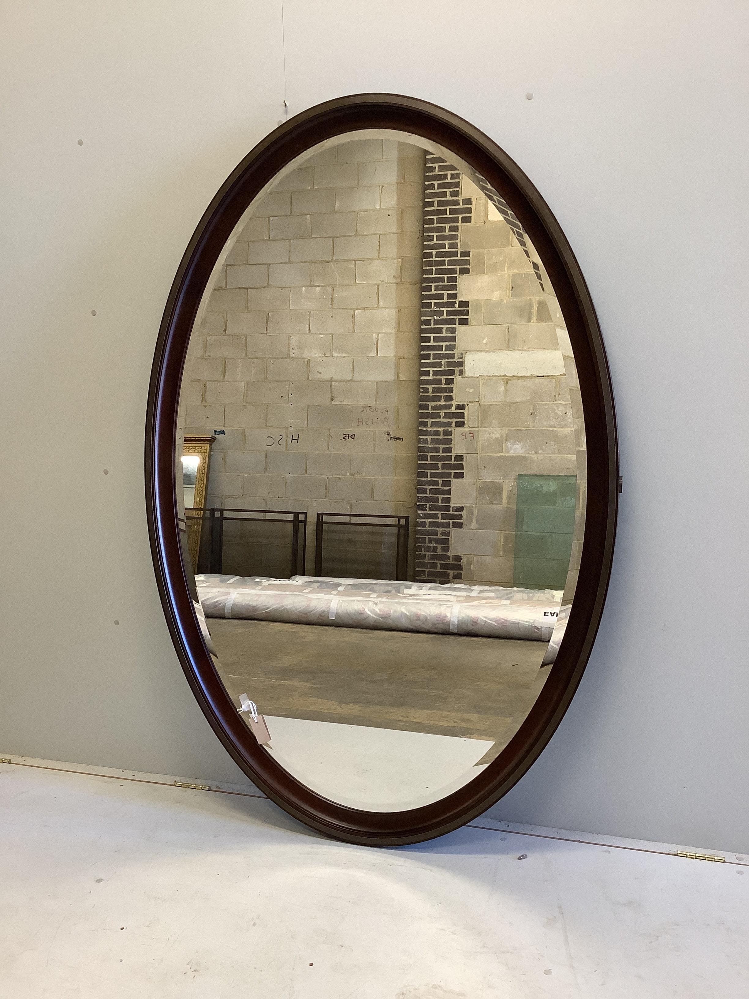 A large bespoke oval brass mounted mahogany mirror by Archer and Smith, width 118cm, height 179cm, and metal wall bracket
